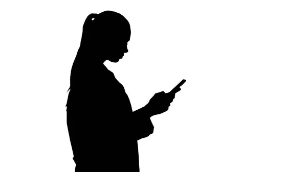 Silhouette Allegro carino giovane donna medico digitando testo sul telefono mentre si cammina. — Foto Stock