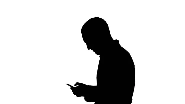 Silhouet Man arts wandelen en aandachtig kijken naar scherm van cellphone. Attantion zingen in het einde maken. — Stockfoto