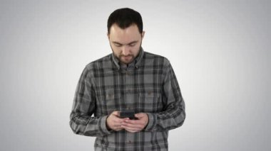 Genç adam yürüyor ve gradyan arka planda akıllı telefon kullanıyor.
