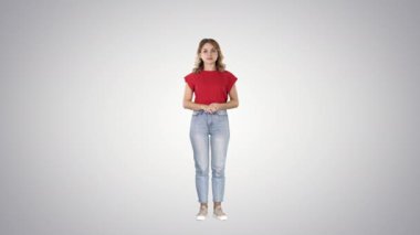 Ayakta ve degrade arka plan üzerinde bekleyen kamera bakarak genç güzel şirin neşeli kadın.