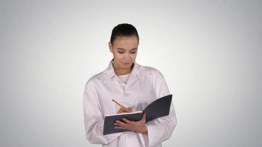 Defter tutan ve degrade arka plan üzerinde yürüme yaratıcı fikir ifade genç kadın doktor.