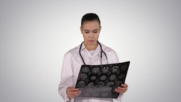 Doctor female with white labcoat, looking at x-ray radiographic image, ct scan, mri on gradient background. — Stock Video