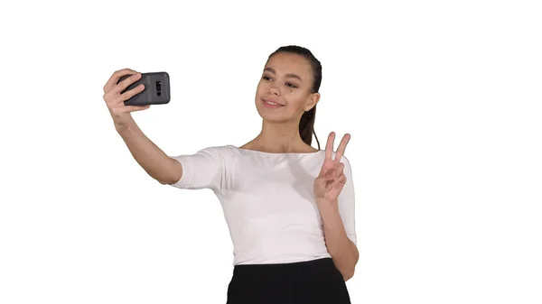 Mujer atractiva sonriente tomando una selfie mientras camina sobre fondo blanco . —  Fotos de Stock