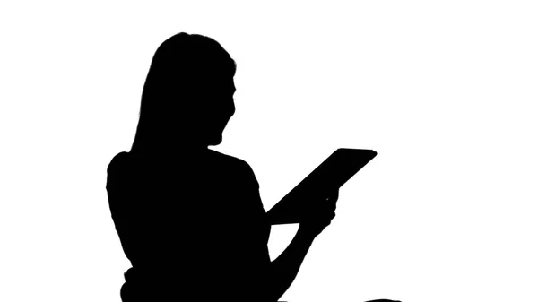 Silhouette Femme assise regardant tablette pc et souriant. — Photo