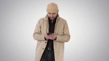 Degrade arka plan üzerinde telefon ile mesajlaşma pelerin genç yakışıklı adam.