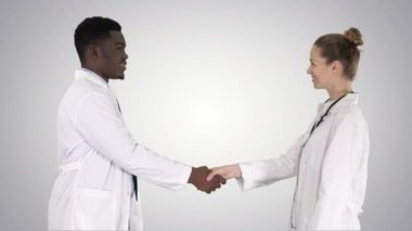 Doktorlar el sıkışıyor ve kameraya gradyan arkaplanda poz veriyorlar.