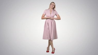 Tam boy portre. Pembe elbiseli sevimli bir kız kamerayla konuşuyor ve arka planda gülümsüyor. 4K çözünürlükte profesyonel atış. 005. Kullanabilirsin, mesela. Ticari videonuzda