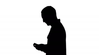Orta ölçekli yan görüş. Siluet Genç akıllı sıradan iş adamı cep telefonundan mesaj okuyor. 4K çözünürlükte profesyonel atış. 004. Kullanabilirsin, mesela. Ticari videonuzda, iş