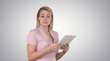 Dijital tablet kullanma ve degrade arka plan üzerinde kameraya konuşurken güzel kadın.