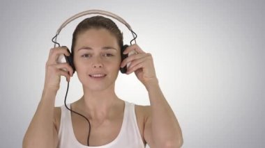 Gülümseyen genç kadın degrade arka plan üzerinde kulaklık ile müzik dinlemek.