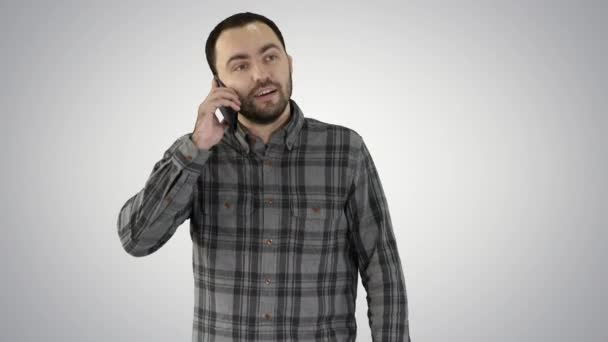 Een man praat aan de telefoon en glimlacht op gradiënt achtergrond. — Stockvideo