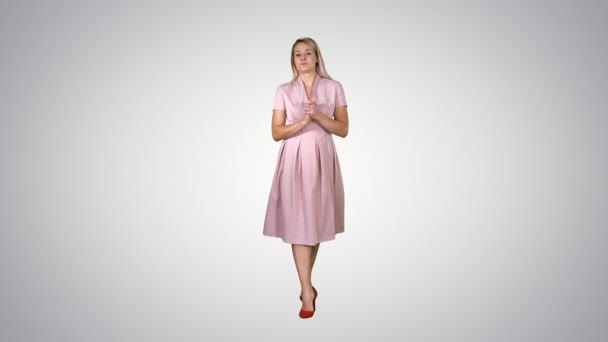 Wanita muda yang bahagia gaun inpink berjalan menuju kamera dan berbicara pada latar belakang gradien . — Stok Video