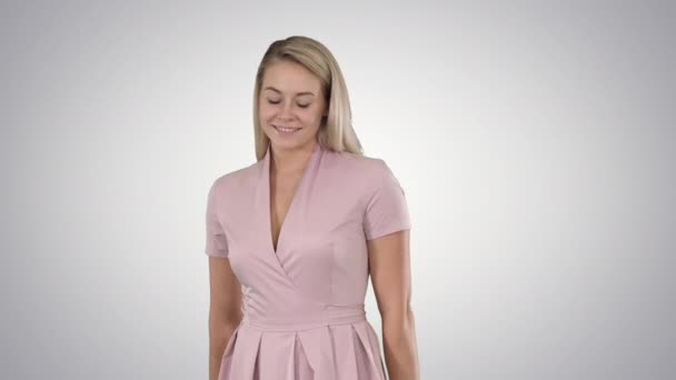 Krásná žena v růžových šatech s úsměvem do kamery, plachost, na pozadí s přechodem. — Stock video