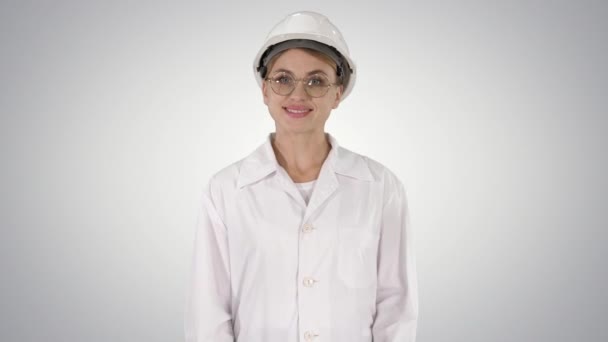 Mujer profesional en bata de laboratorio y gradiente hardhat caminando y sonriendo sobre fondo de gradiente . — Vídeo de stock