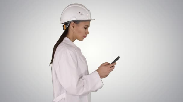 Ingenieur met behulp van mobiele telefoon texting tijdens het lopen op achtergrond met kleurovergang. — Stockvideo