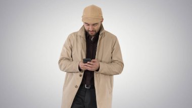 Degrade arka plan üzerinde telefon ile mesajlaşma pelerin genç yakışıklı adam.