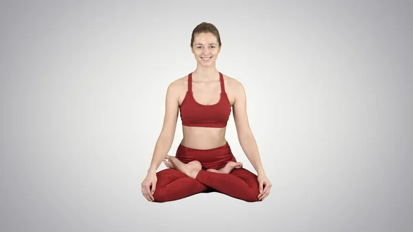 Ung leende kvinna praktisera yoga, göra Padmasana utöva, Lotus pose på tonad bakgrund. — Stockfoto