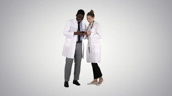 Medical team looking at phone together on gradient background.