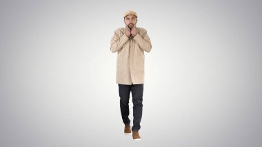 Genç yakışıklı adam yürüyor ve pelerin degrade arka plan üzerinde düğmeleri.