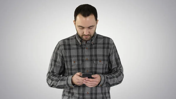 Ung man gå och använda en smartphone på lutning bakgrund. — Stockfoto