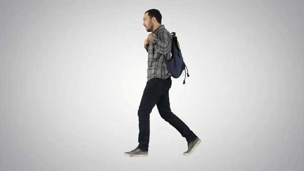Jovem estudante do sexo masculino andando na parede fundo verde com saco e telefone celular no fundo gradiente . — Fotografia de Stock