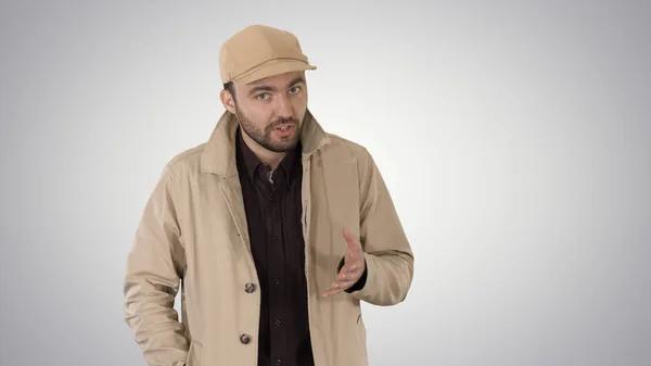 Un mâle à barbe positive vêtu d'un trench coat marchant et parlant sur fond de dégradé . — Photo