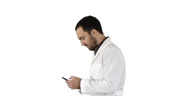 Férfi orvos gyaloglás és figyelmesen nézett a képernyő cellphone gyártás attantion énekel a végén fehér háttér. — Stock Fotó