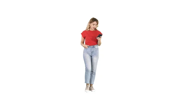 Mujer rubia mensajes de texto con su teléfono inteligente caminando sobre fondo blanco . —  Fotos de Stock