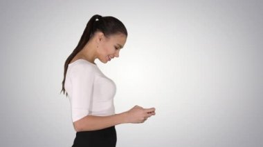 Smartphone kullanarak ve degrade arka plan üzerinde yürüme iş kadını.