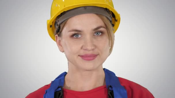 Young woman in yellow hardhat walking on gradient background. — Stock Video
