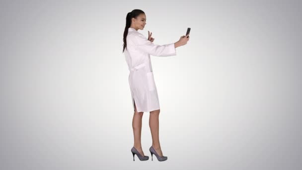 Élégant médecin européen brunette prendre selfie au téléphone tout en marchant sur fond de dégradé. — Video