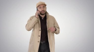 Degrade arka plan üzerinde cep telefonu konuşurken genç moda iş adamı.