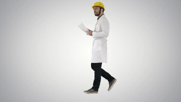 Engineer manager walking with hard hat is holding paper and checking on gradient background. — Stock Video