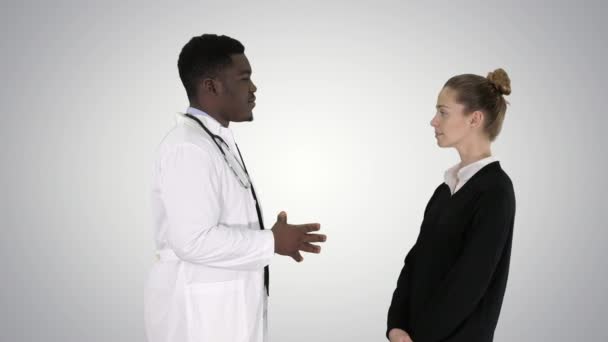 Африканский врач-мужчина разговаривает с пациенткой на градиентном фоне . — стоковое видео