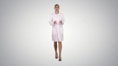Açıklayan ve degrade arka plan üzerinde yürürken kameraya konuşurken kadın doktor.