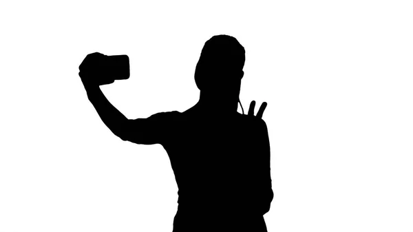 Silhouette Lächelnde attraktive Frau macht beim Gehen ein Selfie. — Stockfoto