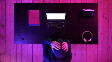 Üzgün oyuncu evde bilgisayarın arkasında oturur ve bilgisayar oyununda yenilgi çığlıkları atar. Beyaz Görünüm.