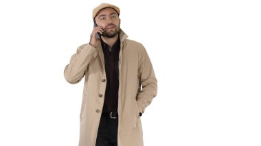 Siper gibi giyinmiş bir adam beyaz arka planda yürürken iş görüşmesi yapıyor..