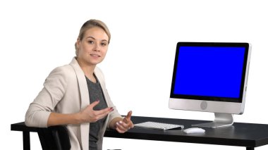 Kameraya konuşmaya ve bir şey bilgisayar, beyaz arka plan ekranda gösterilen genç güzel bayan. Mavi ekran Mock-up.