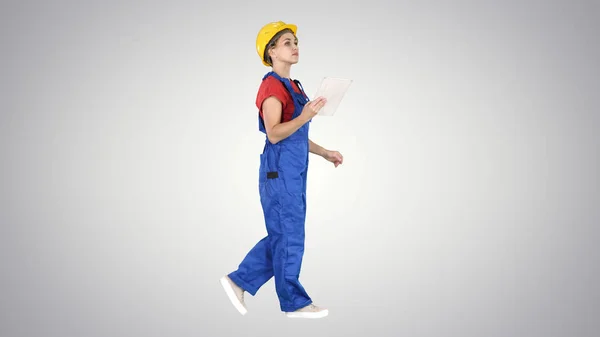 Señora de la construcción usando tableta electrónica caminando sobre fondo de gradiente . — Foto de Stock