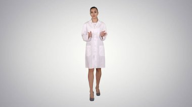 Açıklayan ve degrade arka plan üzerinde yürürken kameraya konuşurken kadın doktor.