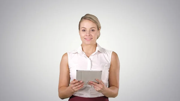 Piękna dziewczyna trzymając tablet touch pad komputera gadżet przesuwając stron i patrząc w aparacie na tło gradientowe. — Zdjęcie stockowe