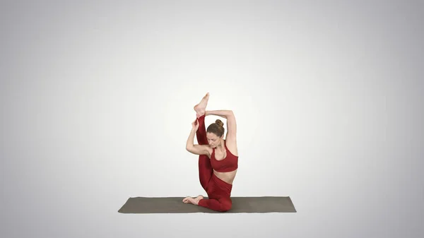 Sportig yogi tjej gör fitness praktiken sträcker sig, yoga asana Parivritta Kraunchasana på tonad bakgrund. — Stockfoto