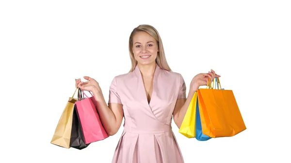 Покупательница счастливо улыбается, держа в руках сумки с покупками и гуляя на белом фоне. — стоковое фото