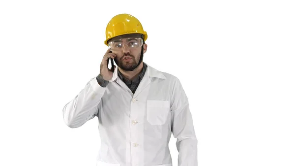 白い背景の電話を取りながら、保護メガネと帽子の歩行のエンジニア. — ストック写真
