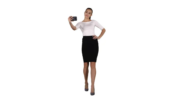 Mujer atractiva sonriente tomando una selfie mientras camina sobre fondo blanco . —  Fotos de Stock