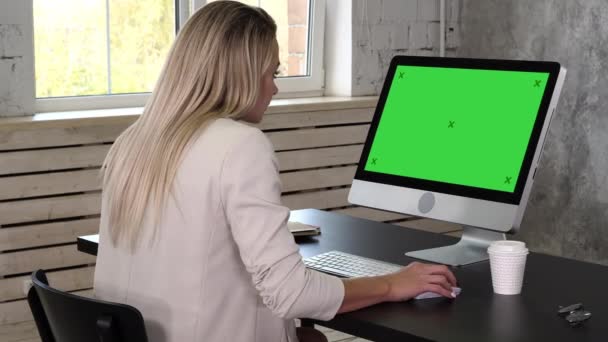 Business kvinna i klänning sitter på arbetsplatsen nära fönstret och använder dator på kontoret. Mock-up-grön skärm. — Stockvideo
