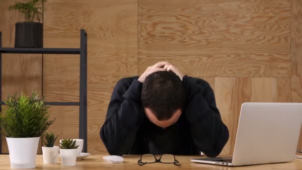頭を抱えた不満のビジネスマンがオフィスで座っています。. — ストック動画
