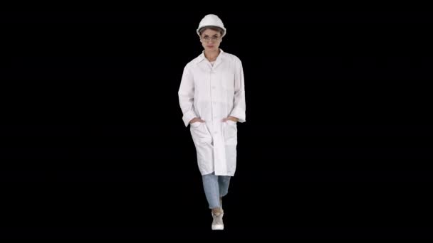 Mujer con una bata de laboratorio blanca y sombrero duro caminando, Alpha Channel — Vídeos de Stock