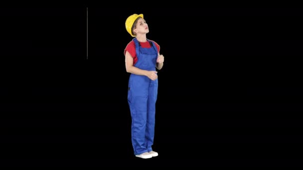 Ingeniera mujer en casco amarillo mirando hacia arriba sorprendida en un edificio o estadística o gráfico, Alpha Channel — Vídeos de Stock